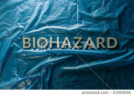 the word biohazard laid with silver letters on blue crumpled plastic film background in flat lay composition at center 83969896