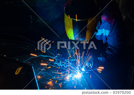 A process of manual operational semi-automatic electric MIG welding with sparks, ndustrial worker in protective mask. A process of manual operational semi-automatic electric MIG welding with sparks, ndustrial worker in protective mask. 83970200