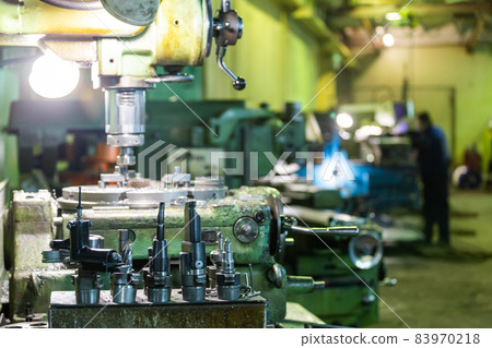 A set of metalworking tools in front of manual vertical milling and boring oldschool machine indoors A set of metalworking tools in front of manual vertical milling and boring oldschool machine indoors 83970218