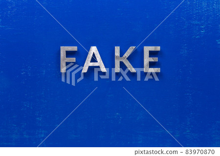 the word fake laid with silver metal characters on blue painted wooden board in central flat lay composition the word fake laid with silver metal characters on blue painted wooden board in central flat lay composition 83970870