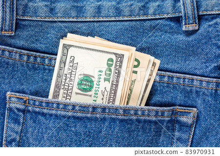 US dollar banknotes in the left rear pocket of blue jeans. Concept of saving money or pocket expenses 83970931