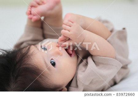 Half-year-old baby licking his feet 83972660