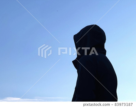 Suspicious man in hood_blue sky background 83973187
