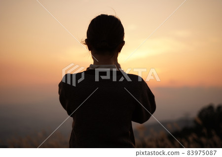 A woman staring at the dusk sky [backlit] 83975087