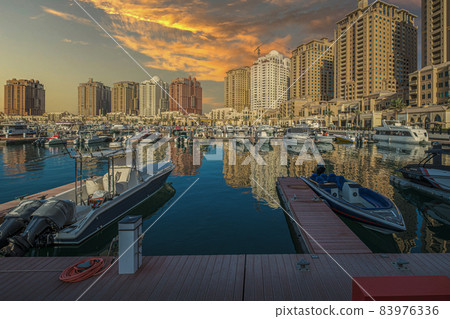 Porto Arabia Marina in The pearl Doha, Qatar sunset  shot showing luxurious yachts docked at the marina with  residential buildings in background. 83976336