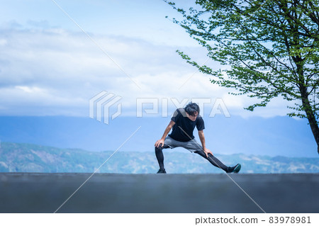 A man doing preparatory exercise in the park (bending and stretching) 83978981