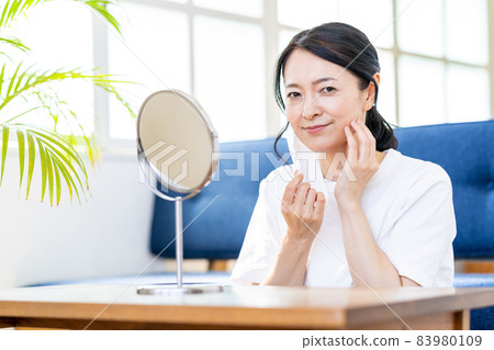 Middle-aged woman checking the condition of her skin due to mask trouble Middle-aged woman checking the condition of her skin due to mask trouble 83980109