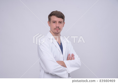 Portrait of young caucasian male medical doctor in white medical gown standing with crossed arms. Isolated on white. Looking at camera with copy space 83980469