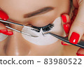 Eyelash Extension Procedure. Woman Eye with Long Eyelashes. Close up, selective focus. 83980522
