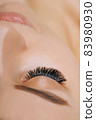 Eyelash Extension Procedure. Woman Eye with Long Eyelashes. Close up, selective focus. 83980930