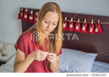 Woman making Christmas advent calendar. Pouches on a rope Woman making Christmas advent calendar. Pouches on a rope 83981207