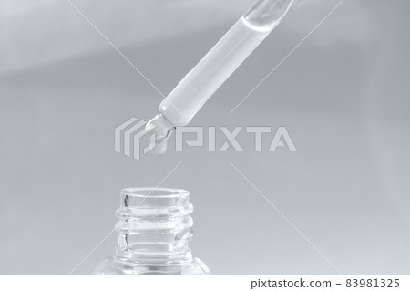 Pipette with transparent fluid hyaluronic acid or serum. Cosmetics, science and healthcare concept closeup. Dose of serum or retinol falls in a bottle. Front view. Beauty product presentation, macro Pipette with transparent fluid hyaluronic acid or serum. Cosmetics, science and healthcare concept closeup. Dose of serum or retinol falls in a bottle. Front view. Beauty product presentation, macro 83981325