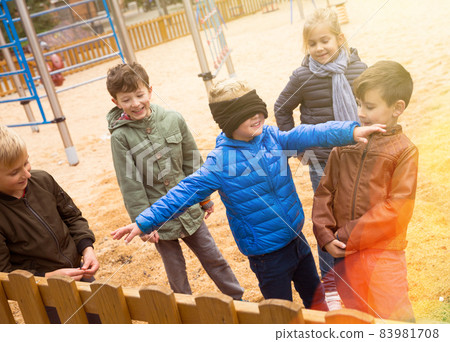 Blindfolded boy catching other children 83981708