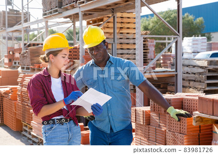 Manager and worker of construction store keep records of brick 83981726