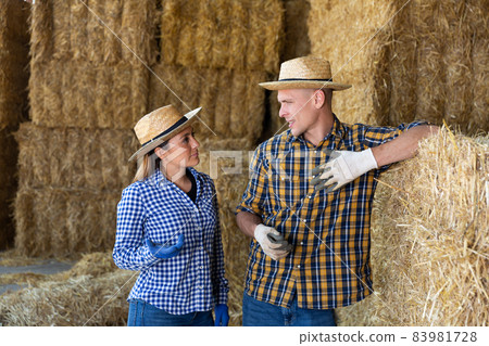 Two confident farmers talking at hay storage 83981728