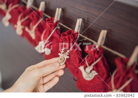 Woman making Christmas advent calendar. Pouches on a rope Woman making Christmas advent calendar. Pouches on a rope 83982042