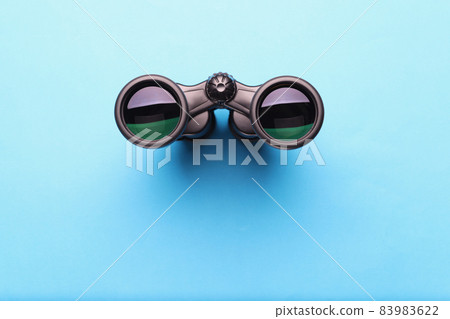 Binoculars equipment placed on blue background with shadow 83983622