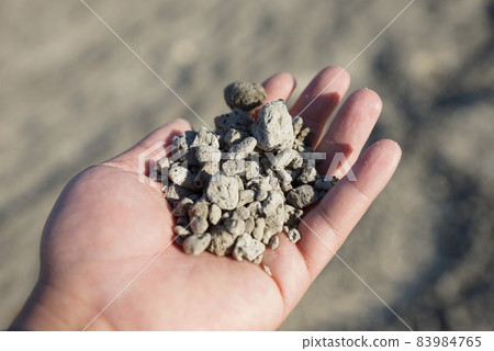 Hand holding a pumice stone falling on the beach of Okinawa 83984765