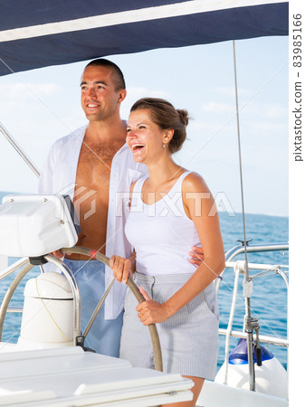 Man and woman steering pleasure yacht Man and woman steering pleasure yacht 83985166