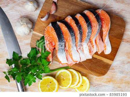 Raw steaks of salmon with seasonings on wooden background Raw steaks of salmon with seasonings on wooden background 83985193
