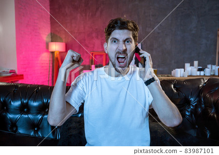 Young man watching football game on television, celebrating goal 83987101