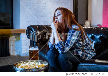 Young emotional attractive woman alone at home sofa couch watchi Young emotional attractive woman alone at home sofa couch watchi 83987103