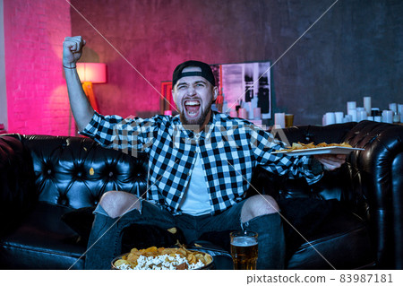 Young fanatic man watching football game on television nervous a 83987181