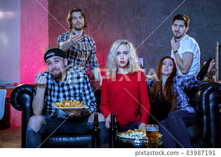 Five cheerful friends hanging out in an apartment and watching a Five cheerful friends hanging out in an apartment and watching a 83987191