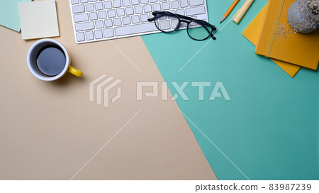 Top view wireless keyboard, coffee cup and notebook on colorful background. 83987239