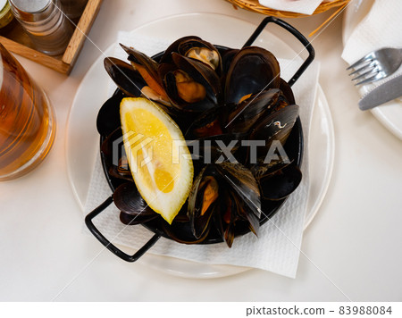 Steamed mussels with lemon wedge in metal serving pan Steamed mussels with lemon wedge in metal serving pan 83988084