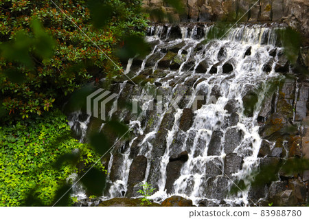 View of a small artificial waterfall in the park. 83988780