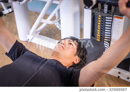 A man doing a bench press at a sports gym A man doing a bench press at a sports gym 83989987