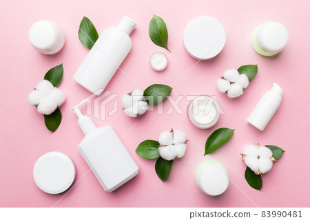 Organic cosmetic products with cotton flower and green leaves on color background. Flat lay 83990481