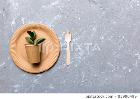 set of empty reusable disposable eco-friendly plates, cups, utensils on light white colored table background. top view. Biodegradable craft dishes. Recycling concept. Close-up 83990499