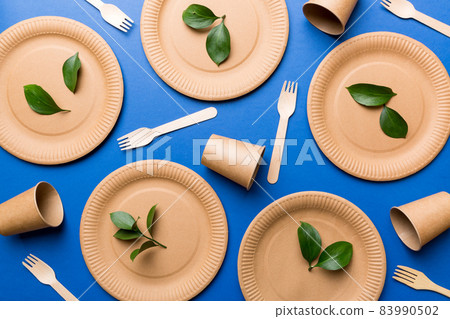set of empty reusable disposable eco-friendly plates, cups, utensils on light white colored table background. top view. Biodegradable craft dishes. Recycling concept. Close-up set of empty reusable disposable eco-friendly plates, cups, utensils on light white colored table background. top view. Biodegradable craft dishes. Recycling concept. Close-up 83990502