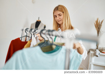 Seamstress choosing dress in atelier, dressmaker 83990889