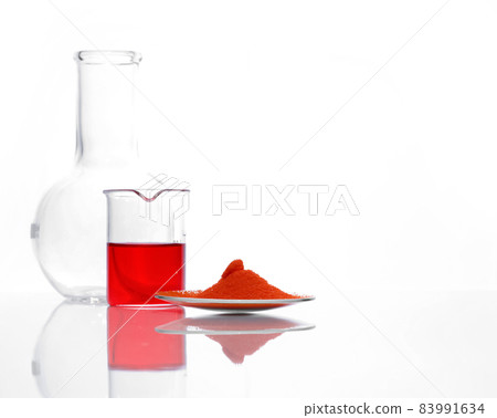 Potassium Dichromate in chemical watch glass place next to Potassium Ferricyanide liquid in beaker and Flat Bottom Flask (Borosilicate Glass) on white laboratory table. Side View 83991634