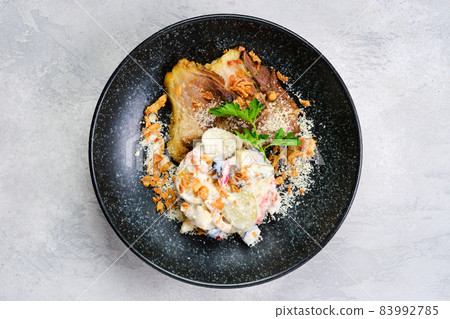 Top view of pickled cucumber with boiled potato and olives served with fried pork belly slices 83992785