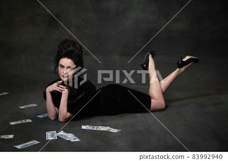 Creative portrait of young adorable woman in image of medieval royal person in black dress isolated on dark vintage background. Creative portrait of young adorable woman in image of medieval royal person in black dress isolated on dark vintage background. 83992940