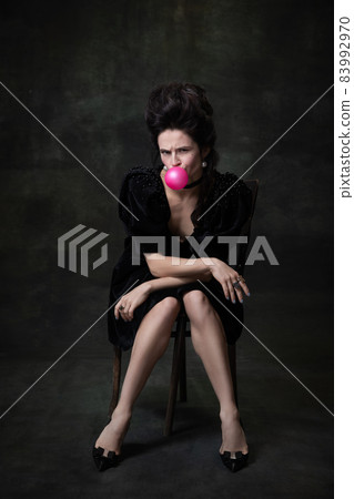 Classic retro portrait of young beautiful woman in image of medieval royal person in black dress isolated on dark vintage background. Classic retro portrait of young beautiful woman in image of medieval royal person in black dress isolated on dark vintage background. 83992970