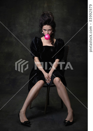 Classic retro portrait of young beautiful woman in image of medieval royal person in black dress isolated on dark vintage background. Classic retro portrait of young beautiful woman in image of medieval royal person in black dress isolated on dark vintage background. 83992979