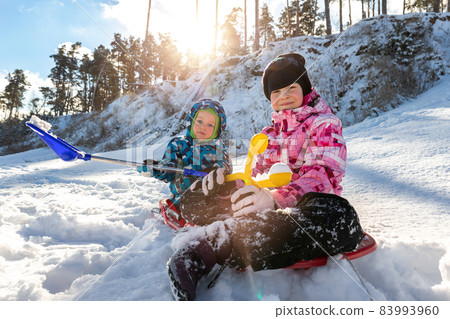 Portrait of two cute adorable little playful children wearing warm snow jacket enjoy having fun playing at park outdoors on sunny cold day. Winter christmas holidays leisure time activities outside Portrait of two cute adorable little playful children wearing warm snow jacket enjoy having fun playing at park outdoors on sunny cold day. Winter christmas holidays leisure time activities outside 83993960