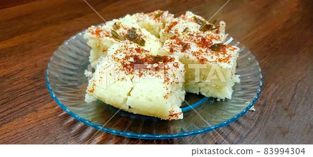 Indian gujarati Traditional Street Food Khaman Dhokla snack made from chick pea flour and rava Served With sev and Chilli Indian gujarati Traditional Street Food Khaman Dhokla snack made from chick pea flour and rava Served With sev and Chilli 83994304