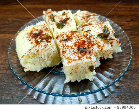 Indian gujarati Traditional Street Food Khaman Dhokla snack made from chick pea flour and rava Served With sev and Chilli 83994306