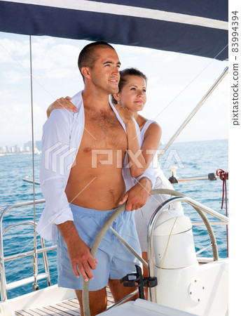 Couple steering yacht along Spanish coast Couple steering yacht along Spanish coast 83994394