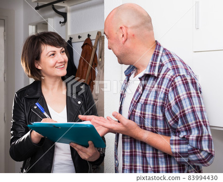 Mature man signing papers with social worker at home near door 83994430