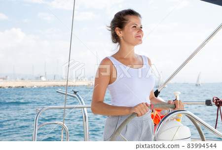 Woman standing at yacht wheel Woman standing at yacht wheel 83994544