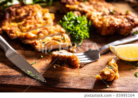 Viennese chicken steak on a fork. Traditional Austrian and German dish of chicken meat and breadcrumbs Viennese chicken steak on a fork. Traditional Austrian and German dish of chicken meat and breadcrumbs 83995104