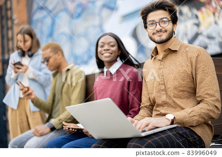 Multiracial students watch some on laptop outdoors 83996049