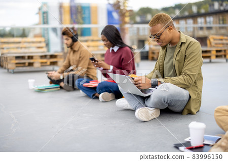 Students sitting and using smartphones on asphalt 83996150